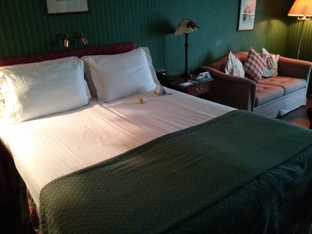 Gemütliches Hotelzimmer mit Bett, Sofa, Nachttisch und Lampen.