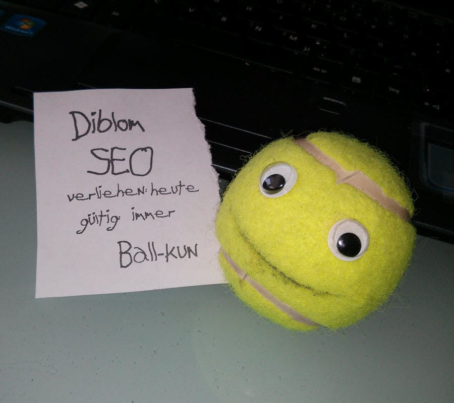 Tennisball mit Augen und Notizzettel auf Tastatur.