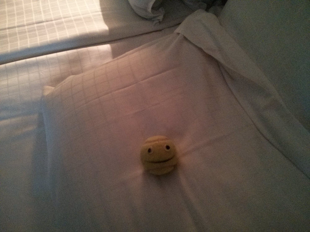 Kleiner, runder Ball mit Gesicht auf einem Bett.