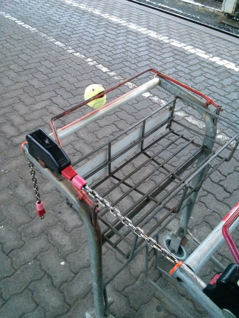 Einkaufswagen mit Kette gesichert auf einem Parkplatz.