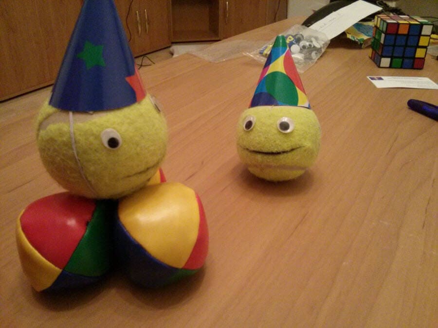 Zwei Bälle mit Partyhüten auf einem Holztisch.