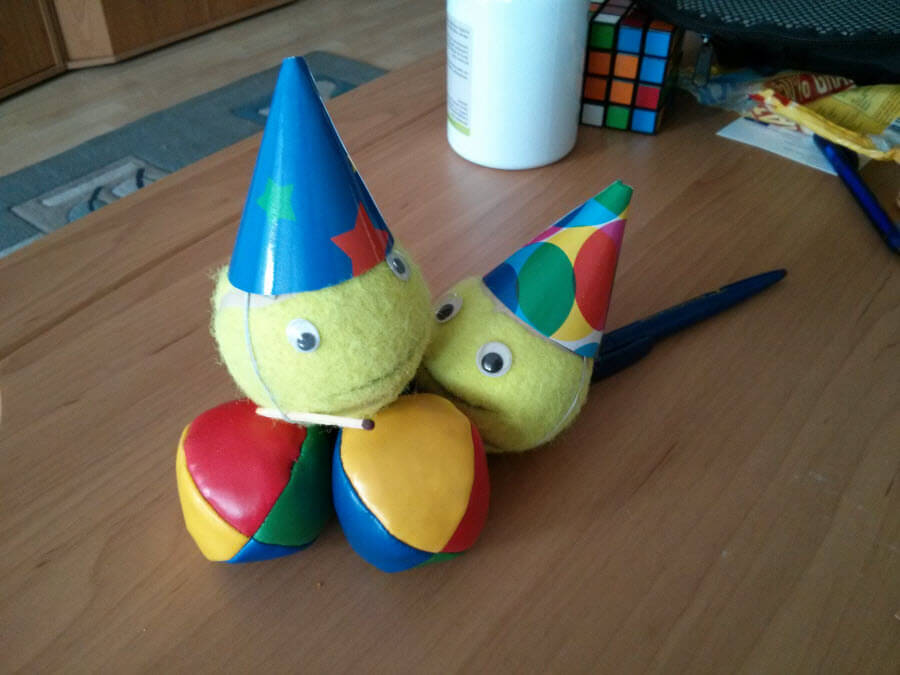Zwei bunte Bälle mit Partyhüten und Augen auf einem Tisch.