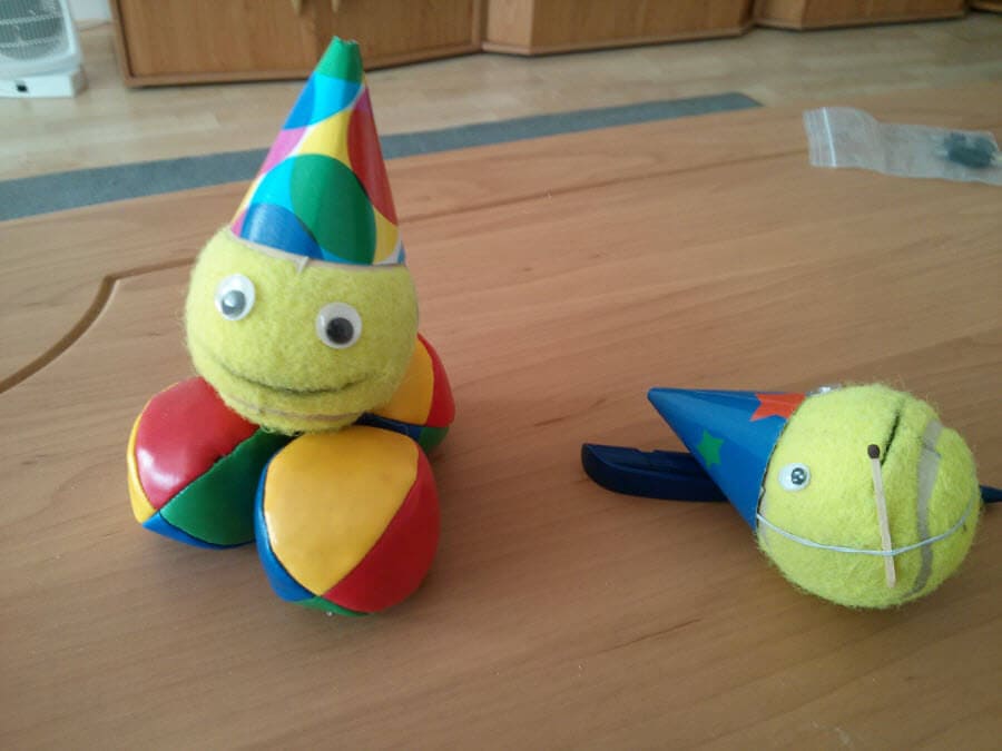 Zwei bunte Bälle mit Partyhüten auf einem Tisch.