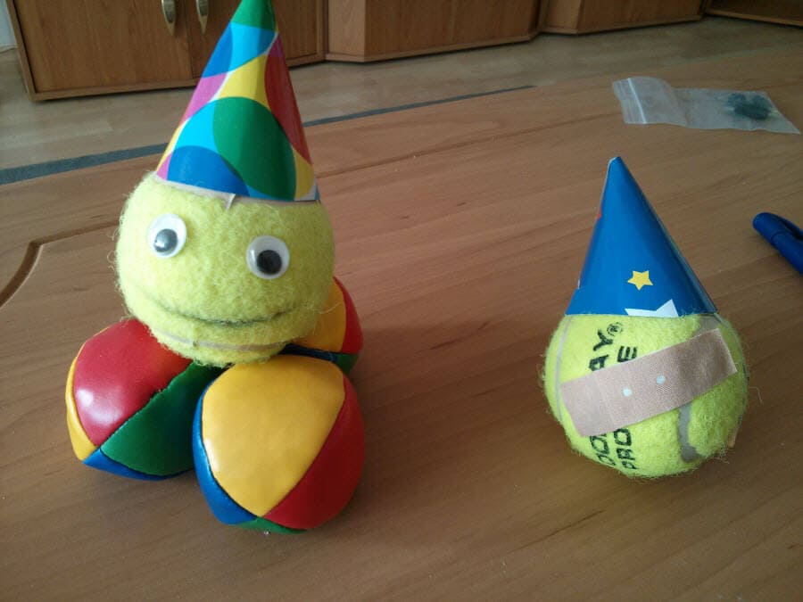 Zwei bunte Bälle mit Partyhüten auf einem Tisch.