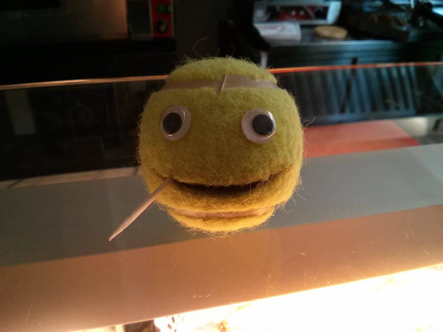 Fellball mit Augen, Zunge und Lutschstiel auf einer Theke.