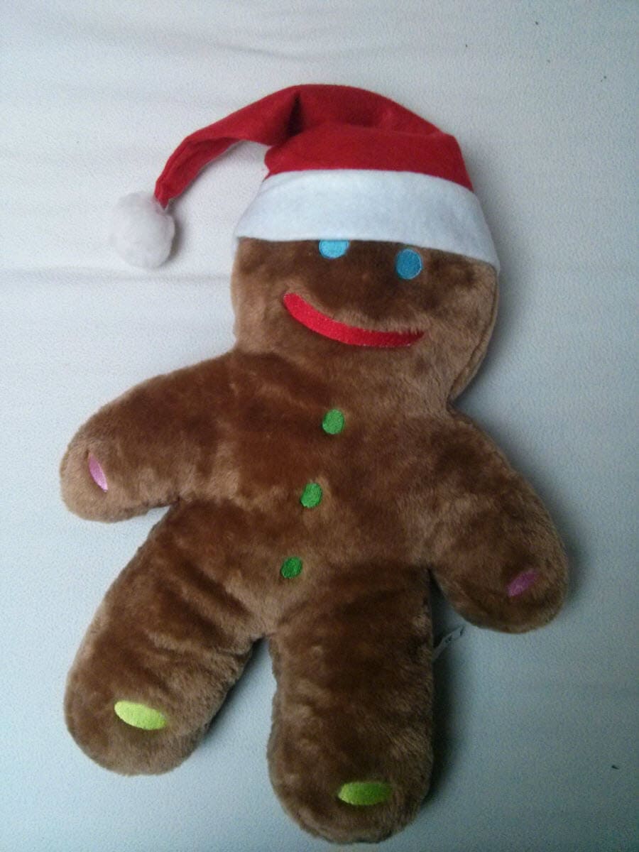 Plüsch-Lebkuchenmann trägt rote Weihnachtsmütze mit weißem Rand.