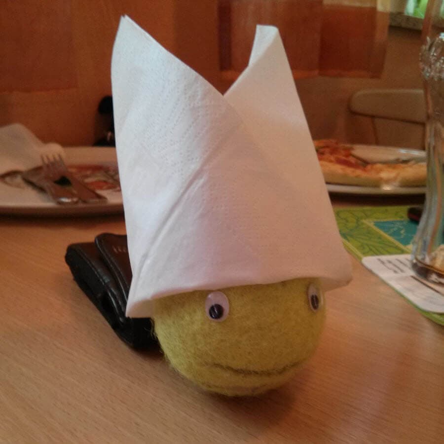 Ball mit Papierhut und Augen auf einem Tisch.