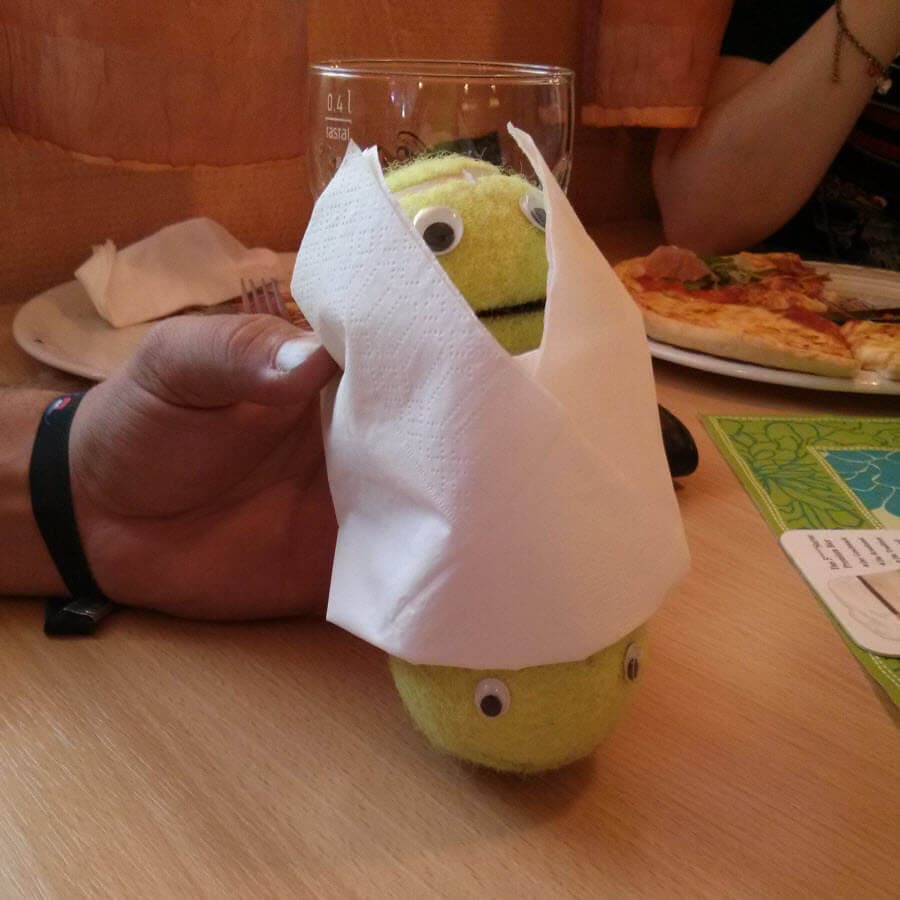 Ball-Kun, ein grüner Ball mit Augen, in einem Papiertuch eingewickelt.