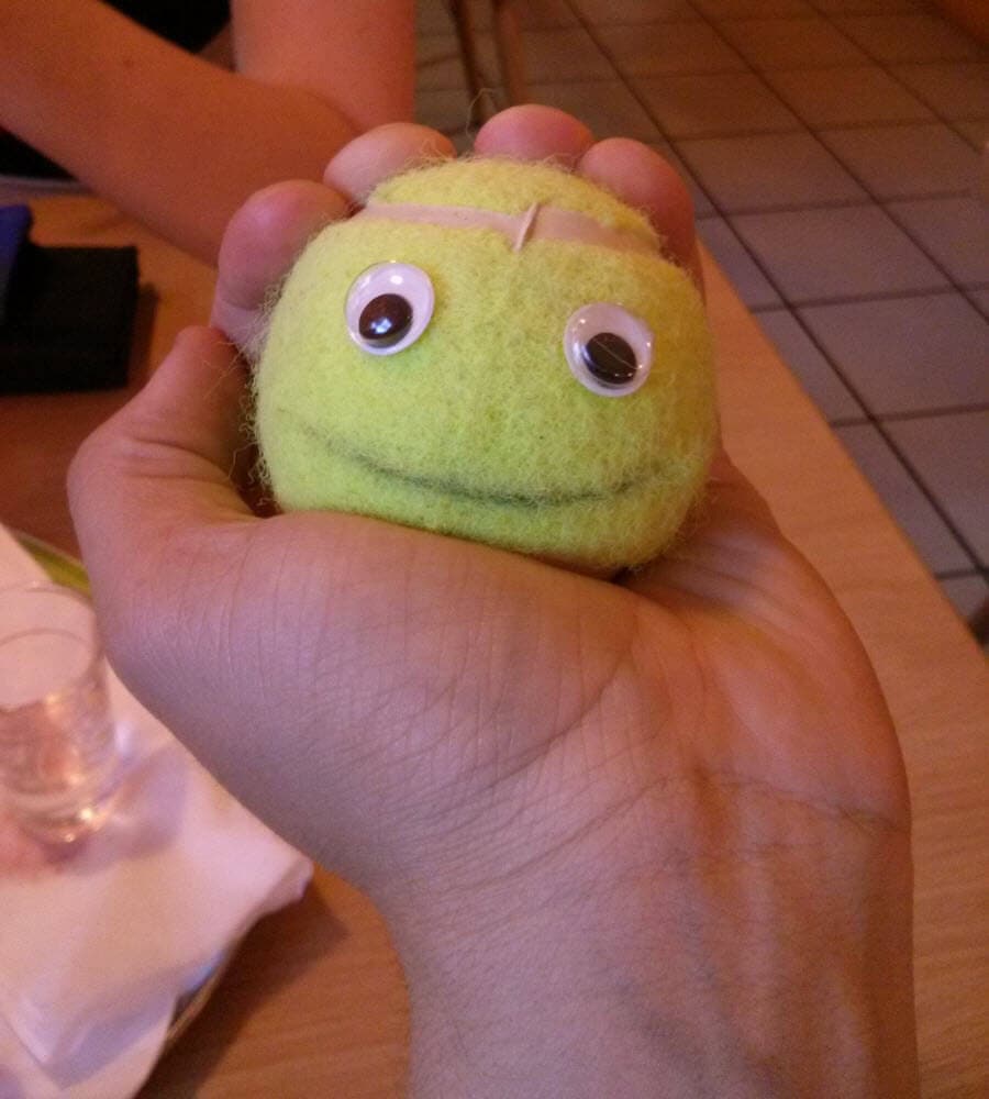 Weicher gelber Ball mit googly eyes in Hand gehalten.