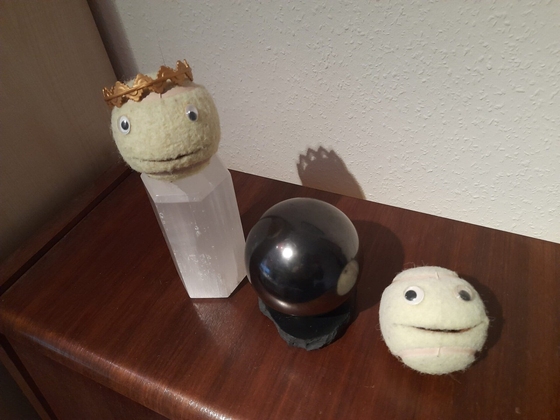 Zwei Ball-Figuren und eine schwarze Kugel auf einem Holztisch.